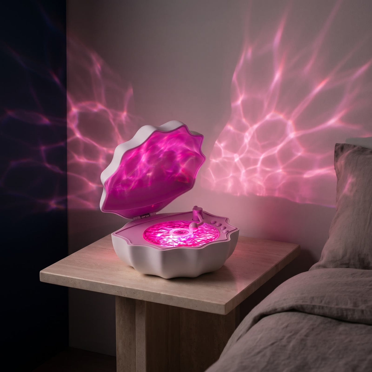 Lampka Lumina Muszelka różowa włączona wieczorem na kamiennej szafce nocnej, różowe fale światła na ścianie